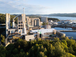 Brevik CCS bygges til venstre og «foran» sementfabrikken, med mellomlagringstanker til høyre på bildet (Foto: Heidelberg Materials/Brevik CCS).