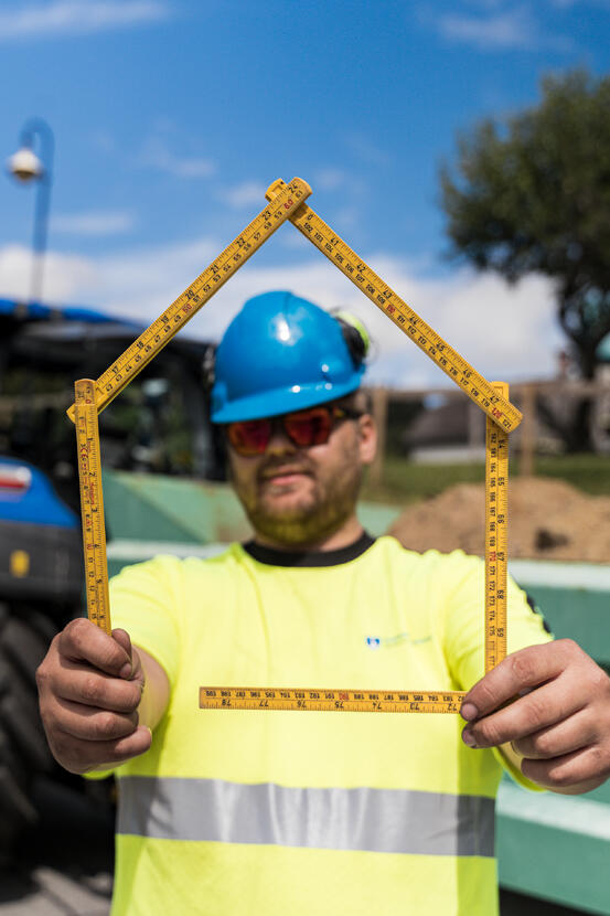 Bygningsarbeider med ein tommestokk forma som eit hus