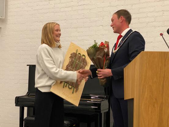 Louise Tveito fekk overrekt kulturprisen frå ordførar Stig Ove Ølmheim i kommunestyremøtet torsdag. (Foto: Mariann Skau) Ung kvinne frå overrekt kunstverk og blomar frå ordførar.