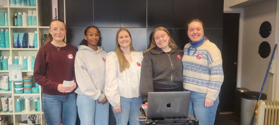 Fem smilande studentar oppstilte i ein frisørsalong.