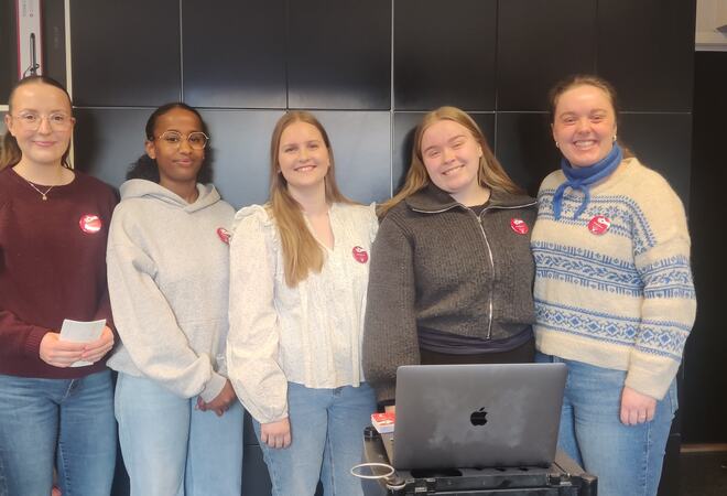 Fem smilande studentar oppstilte i ein frisørsalong.