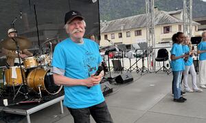 Mann med blå t-skjorte som smiler på scena.